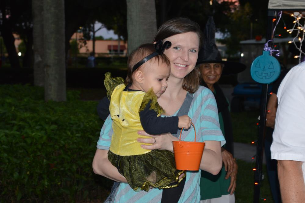 Mom holding baby in yellow dress holding small orange pale